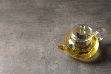 Photo of Glass teapot with oolong on grey table. Space for text