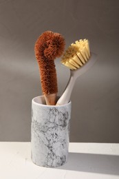 Cleaning brushes in holder on white table, closeup