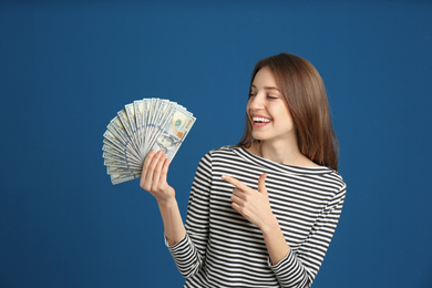 Photo of Happy young woman with cash money on blue background
