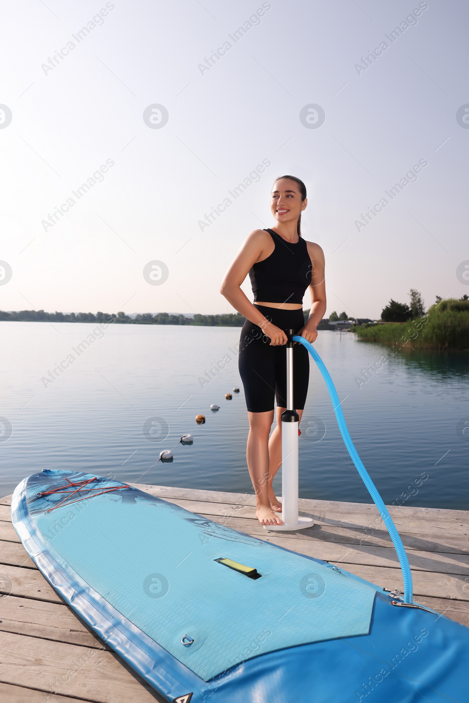 Photo of Woman pumping up SUP board on pier