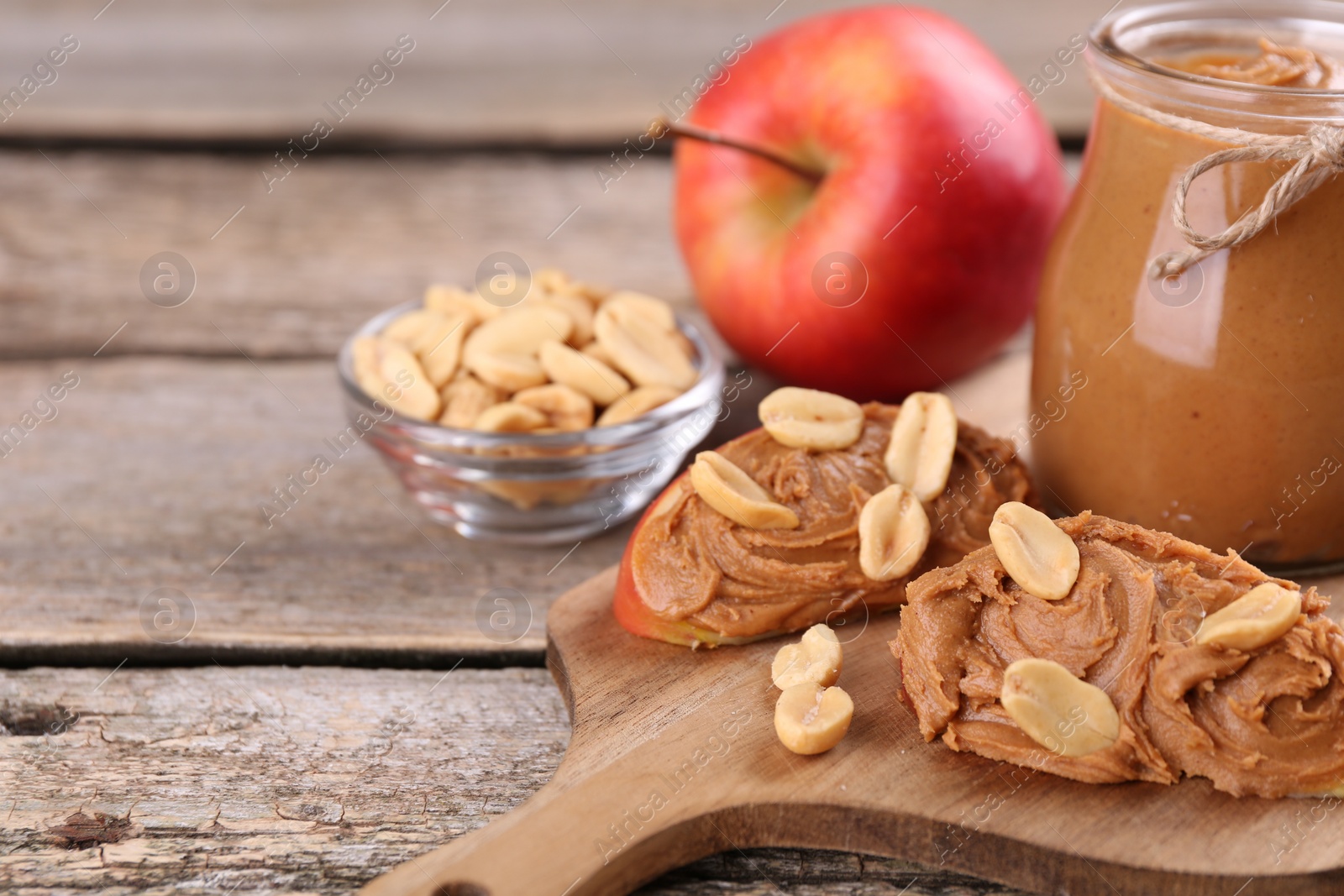 Photo of Fresh apples with peanut butter on wooden table, space for text