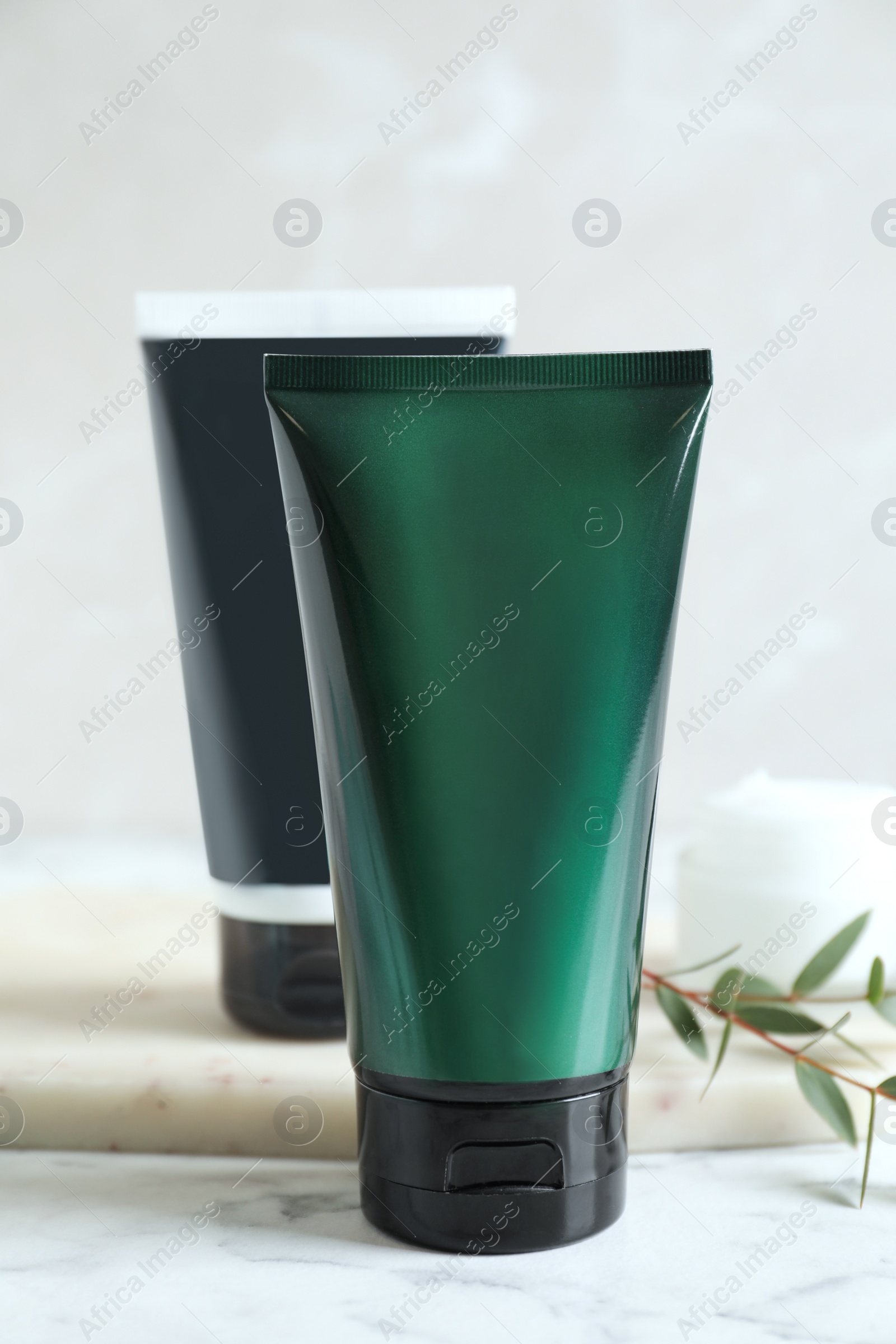 Photo of Tubes and jar of facial cream for men on white marble table