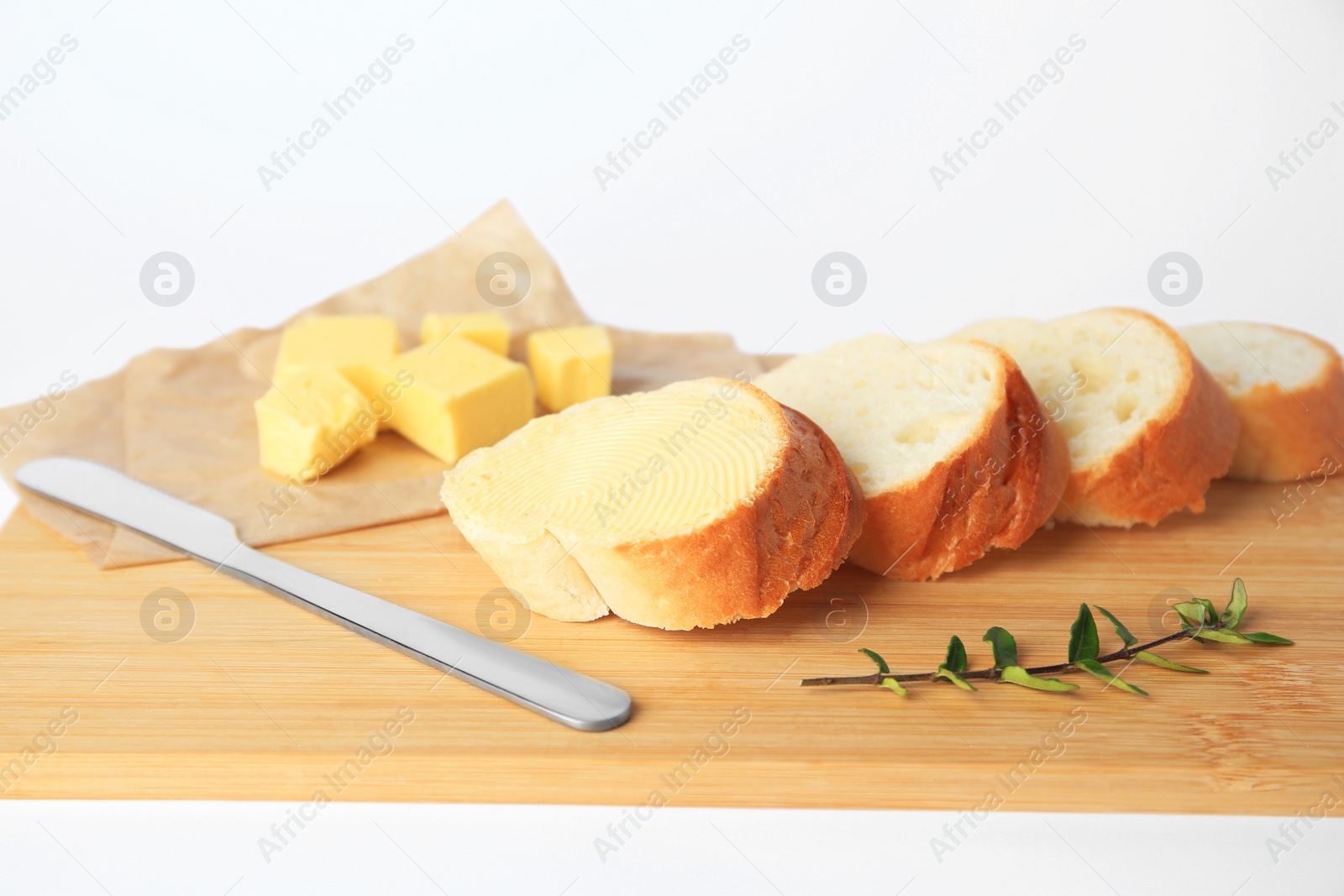 Photo of Wooden board with sliced baguette and fresh butter on white background, closeup