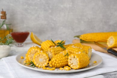 Photo of Plate with tasty cooked corn cobs on table indoors