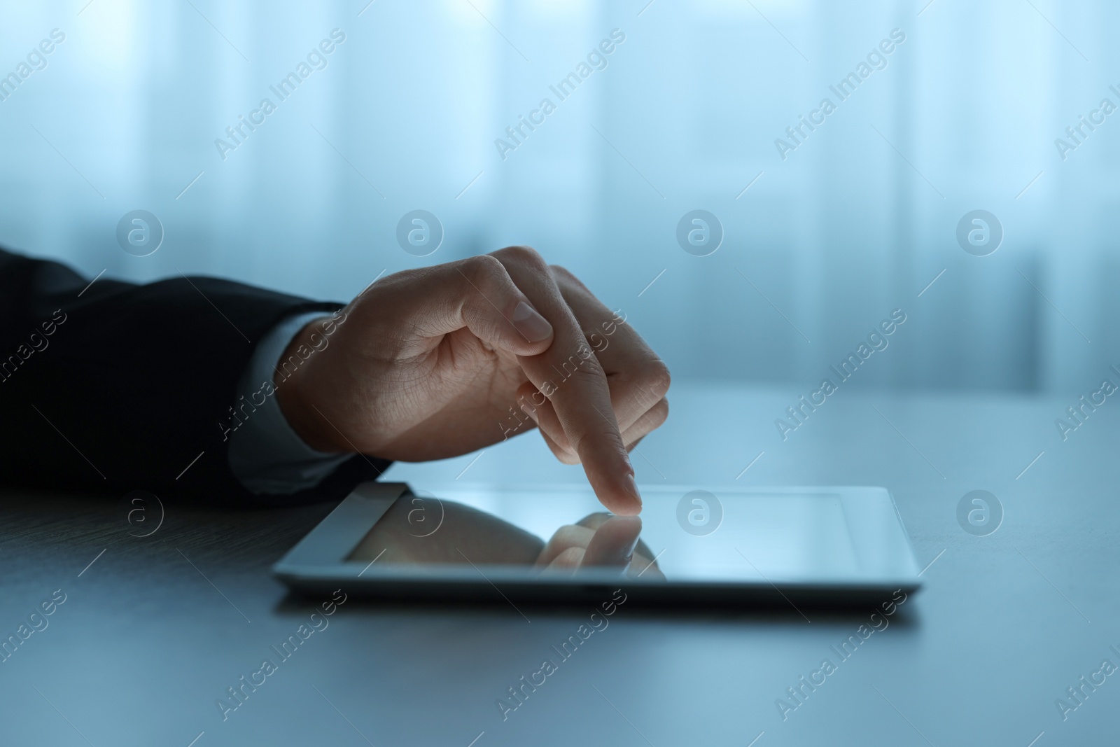 Photo of Man using tablet at wooden table indoors, closeup