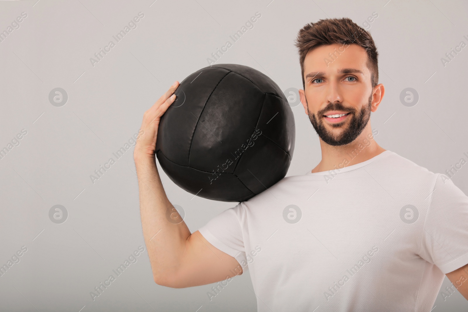 Photo of Athletic man with medicine ball on light grey background
