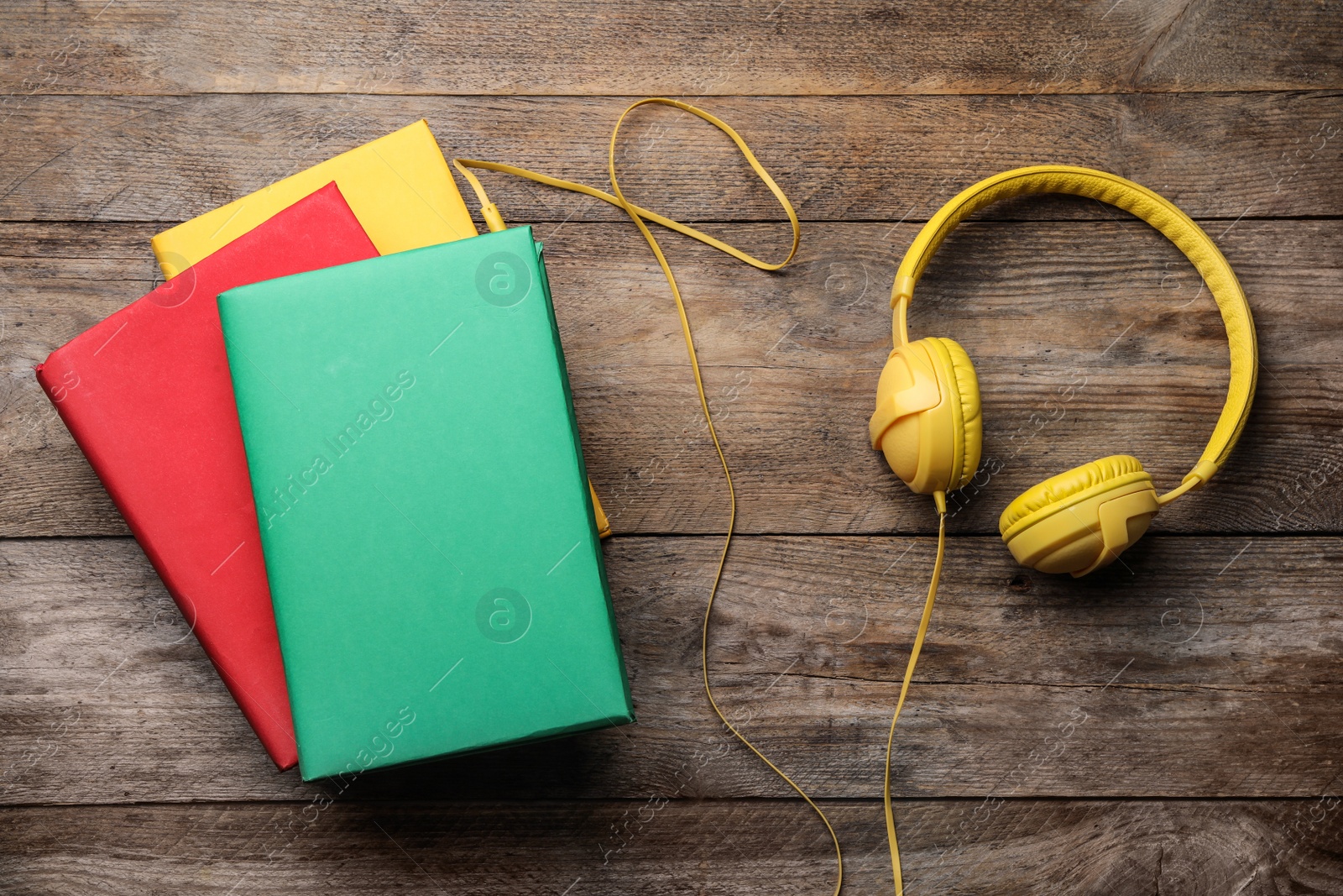 Photo of Books and modern headphones on wooden background, flat lay