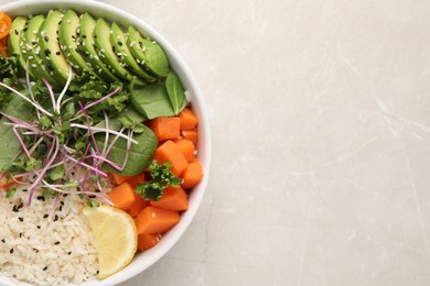 Photo of Delicious vegan bowl with avocados, carrots and microgreens on light grey table, top view. Space for text