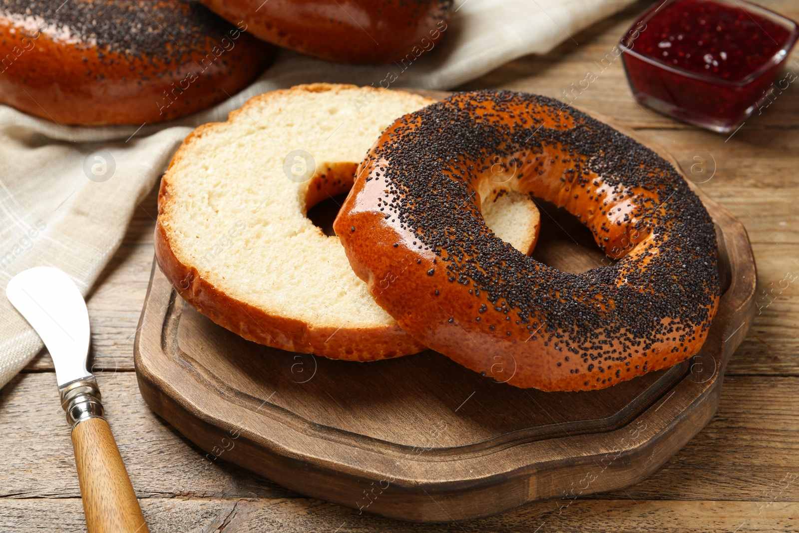 Photo of Delicious fresh bagels with poppy seeds on wooden table