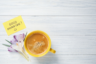 Photo of Delicious coffee, flowers and card with GOOD MORNING wish on white wooden table, flat lay. Space for text
