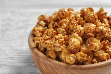 Photo of Delicious popcorn with caramel in bowl on table, closeup