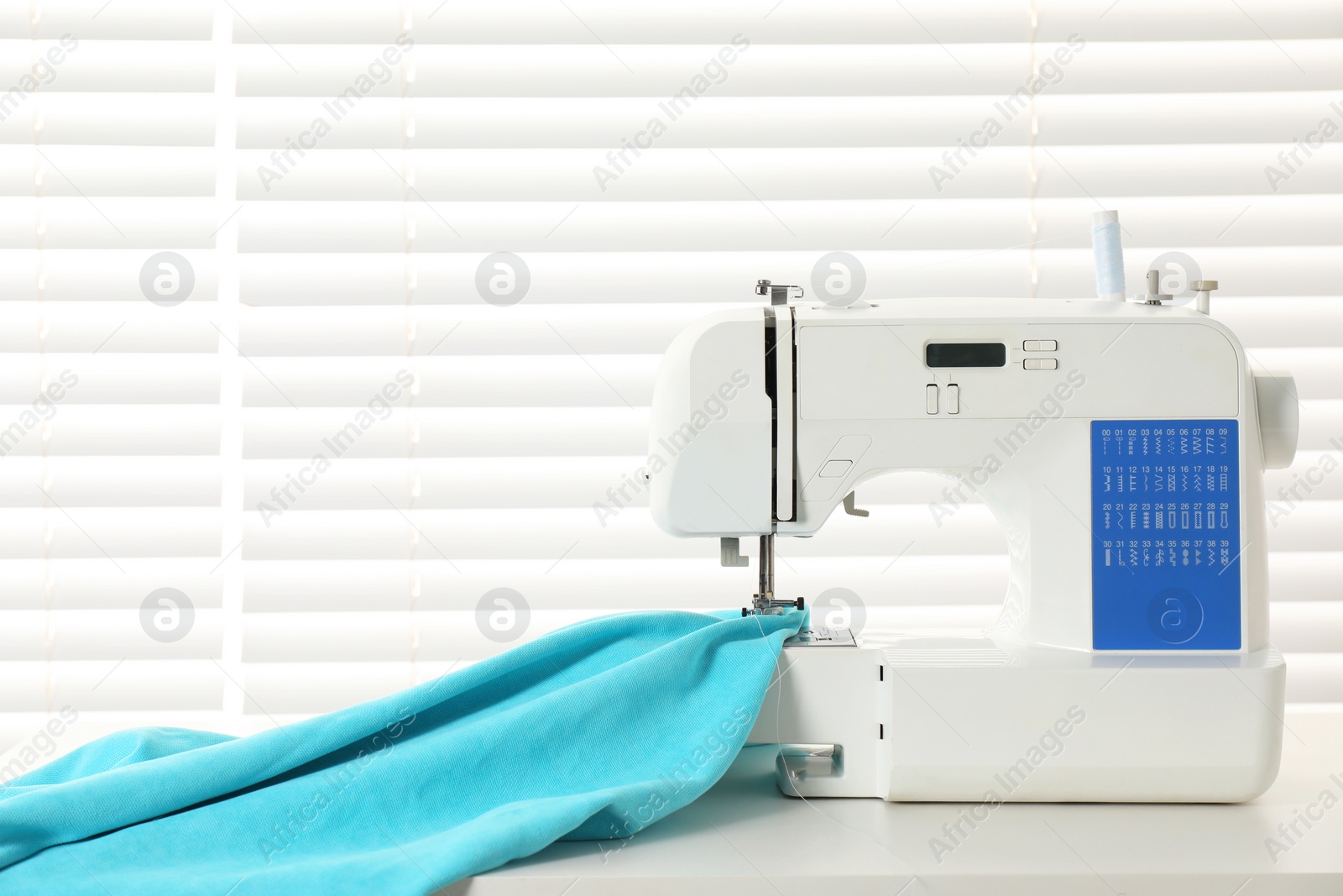 Photo of White sewing machine and fabric on light table indoors