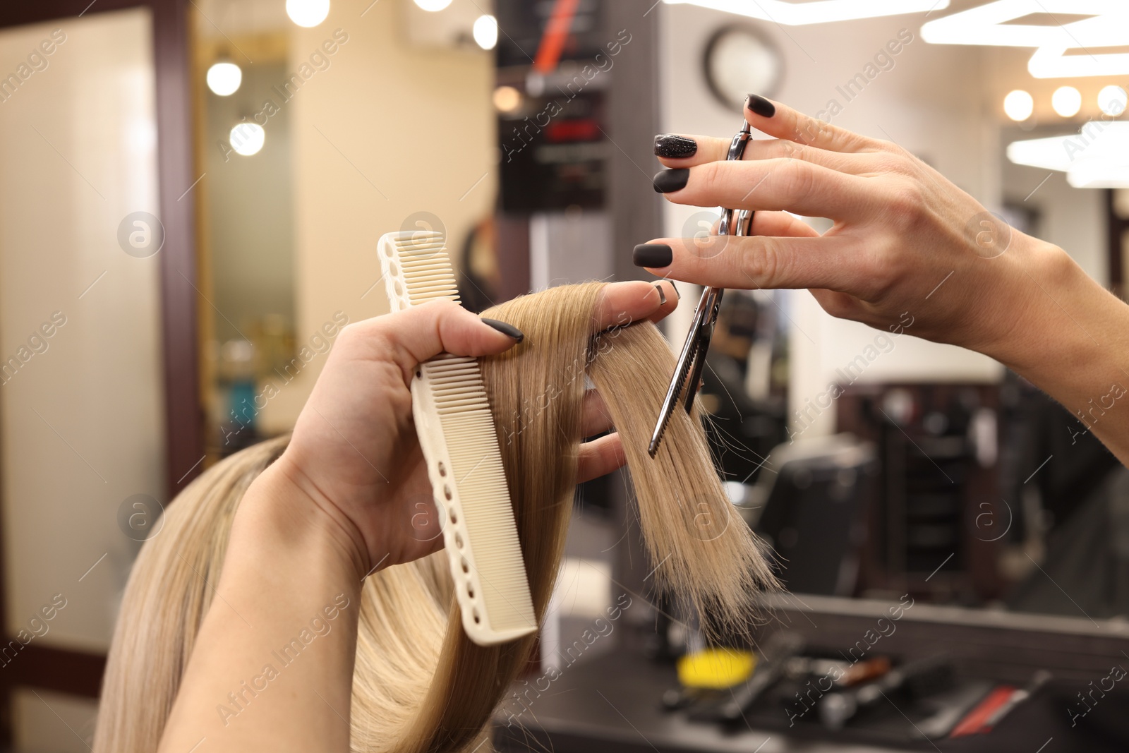 Photo of Professional hairdresser cutting woman's hair in salon, closeup