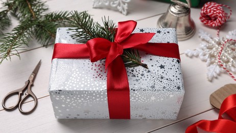 Photo of Beautifully wrapped gift box on white wooden table, closeup