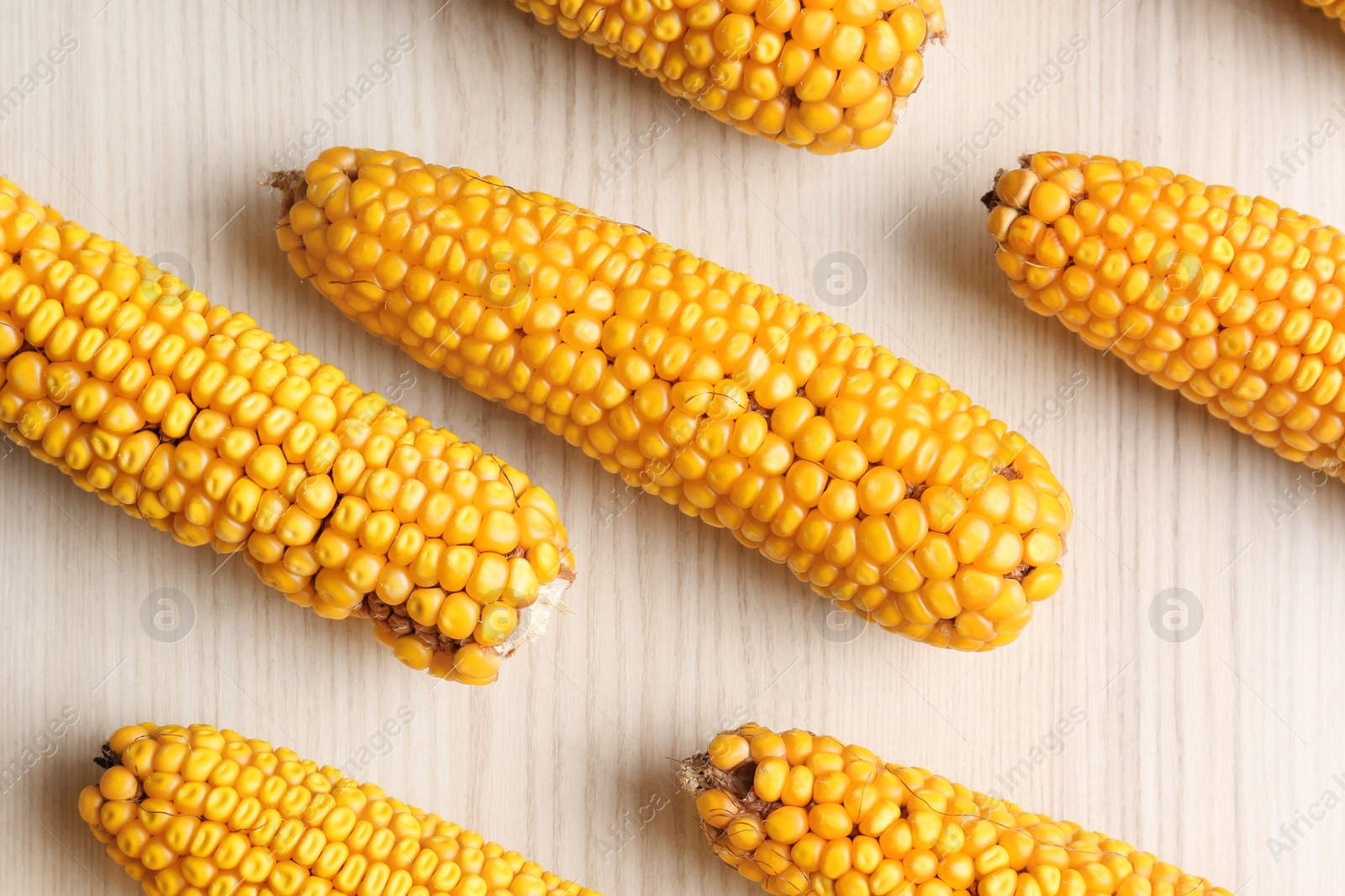 Photo of Delicious ripe corn cobs on white wooden table, flat lay