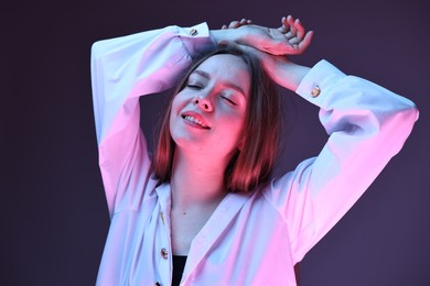 Photo of Fashionable portrait of beautiful young woman on purple background in neon lights