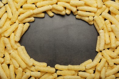 Frame of corn sticks on dark grey table, top view. Space for text