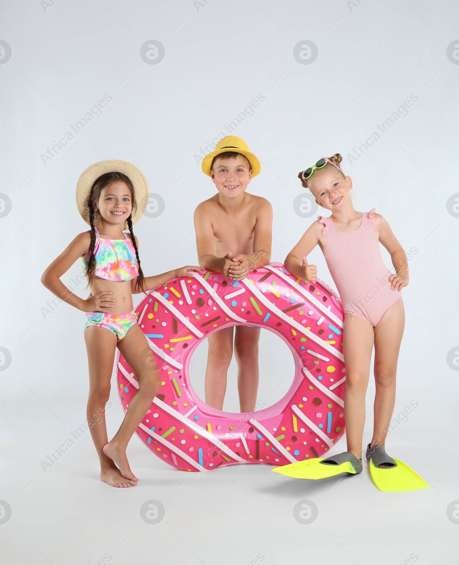 Photo of Cute little children in beachwear with bright inflatable ring on white background