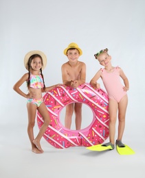 Photo of Cute little children in beachwear with bright inflatable ring on white background