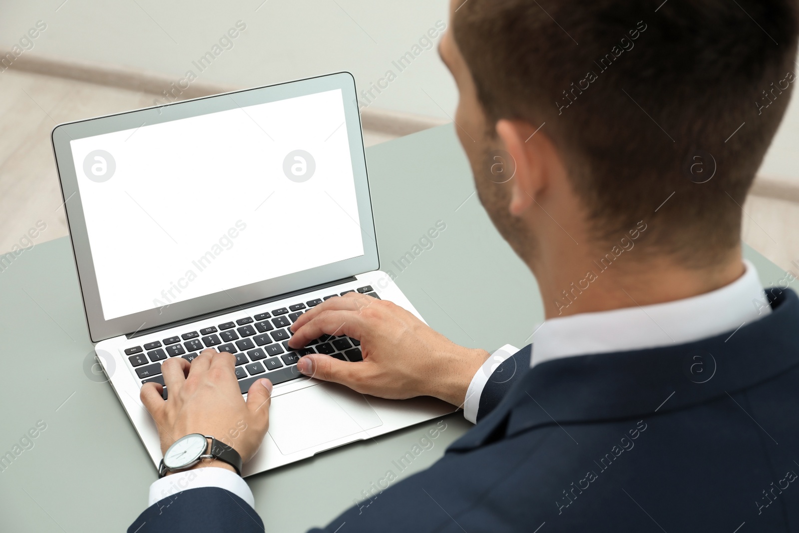 Photo of Man in office wear using laptop at table indoors