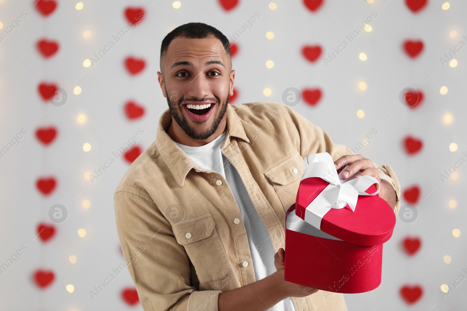 Photo of Handsome man opening gift box from his girlfriend indoors, view from camera. Valentine's day celebration in long distance relationship