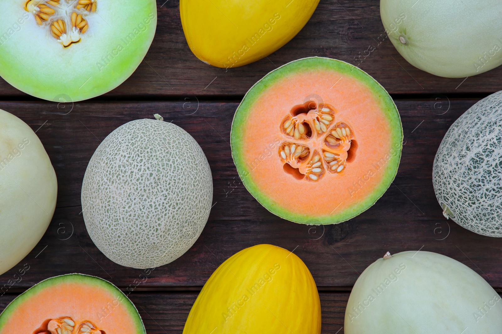 Photo of Different types of tasty ripe melons on wooden table, flat lay