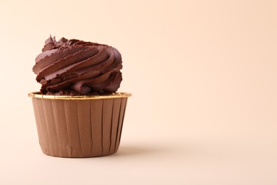 Delicious chocolate cupcake on beige background, closeup. Space for text