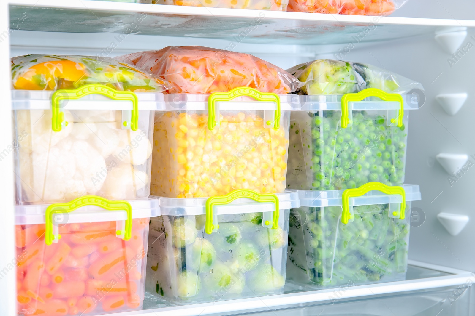 Photo of Containers with deep frozen vegetables in refrigerator