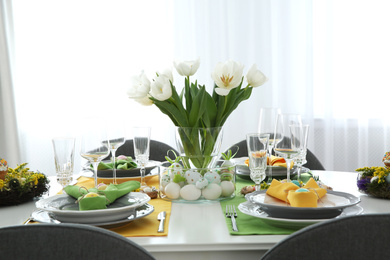 Photo of Festive Easter table setting with beautiful white tulips and eggs indoors