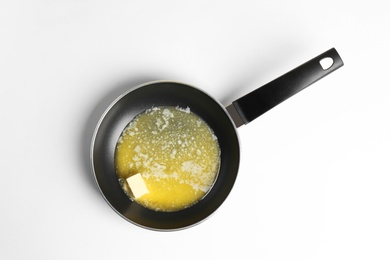 Frying pan with melting butter on white background, top view