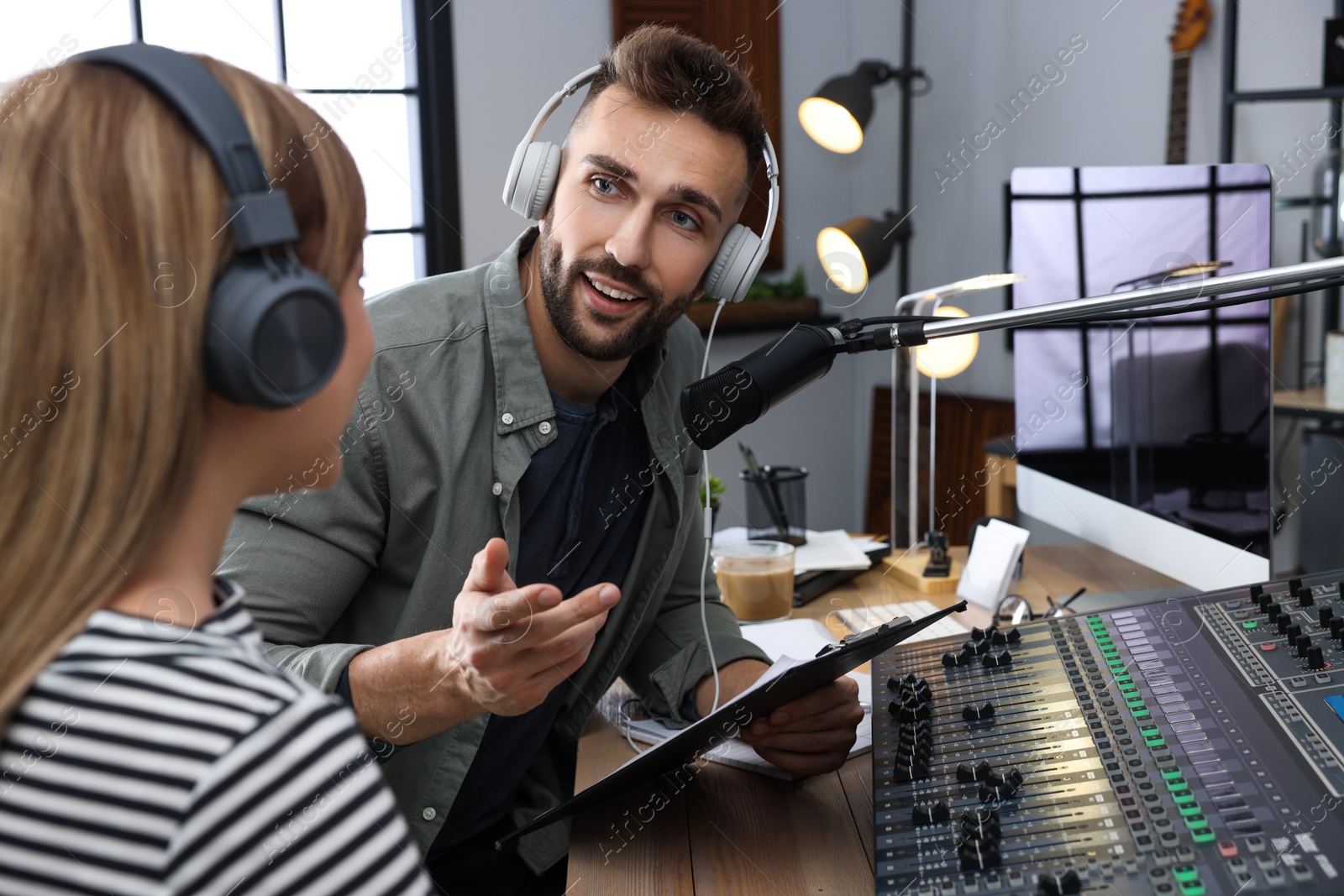 Photo of Man interviewing young woman in modern radio studio