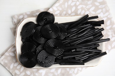 Photo of Tasty black liquorice candies on white wooden table, top view