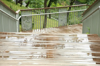 Photo of Wet wooden staircase with puddles outdoors. Rainy weather