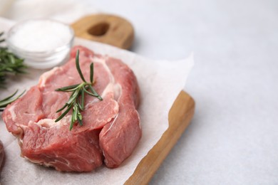 Photo of Fresh raw meat with rosemary on light table, closeup. Space for text