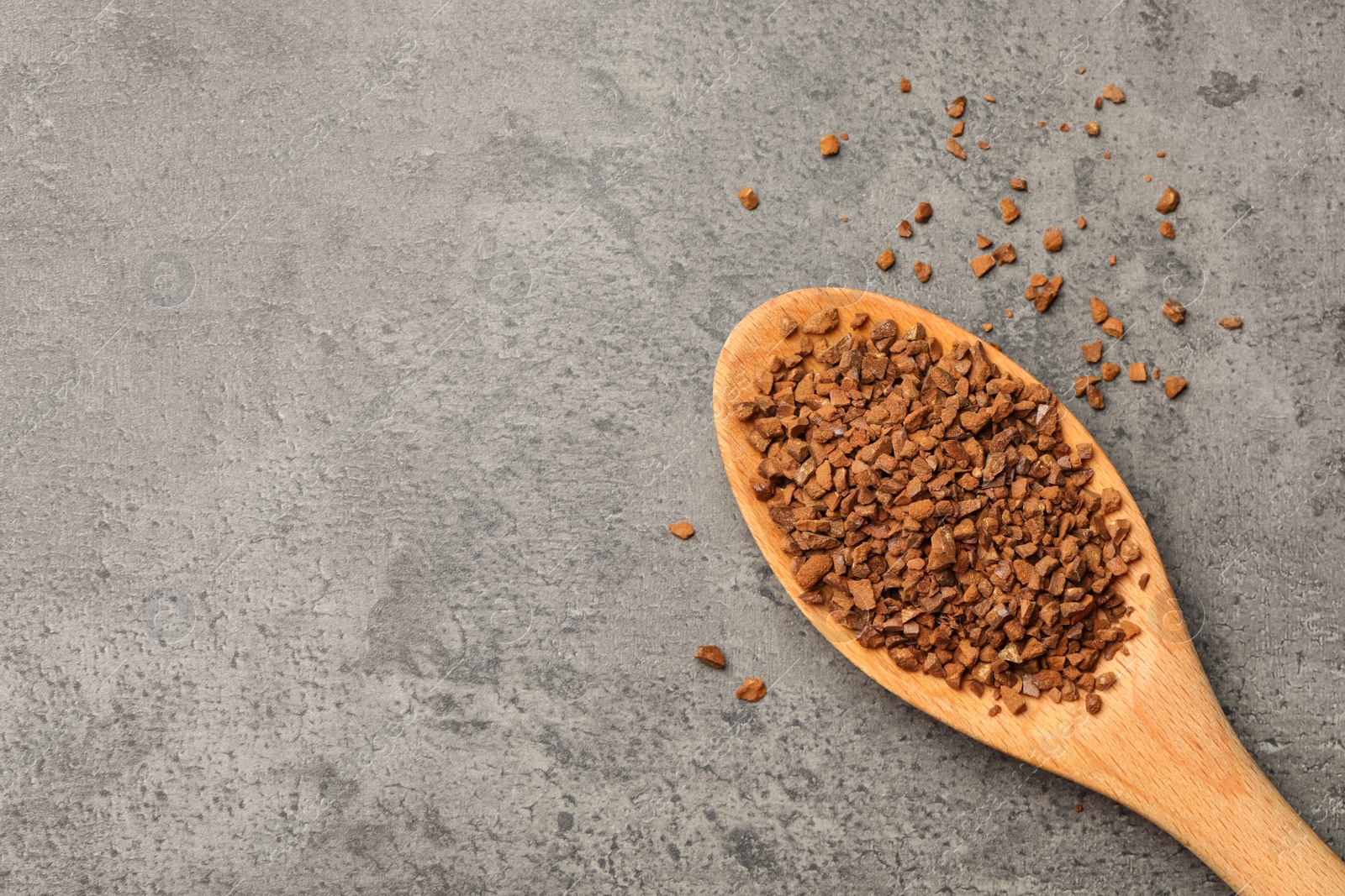 Photo of Spoon of chicory granules on grey table, flat lay. Space for text