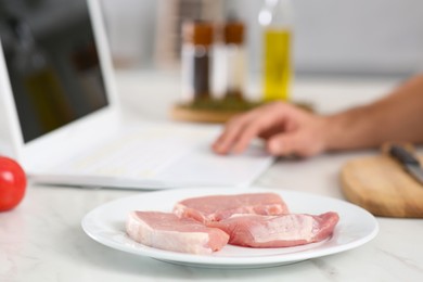 Photo of Man making dinner while watching online cooking course via laptop at table, closeup