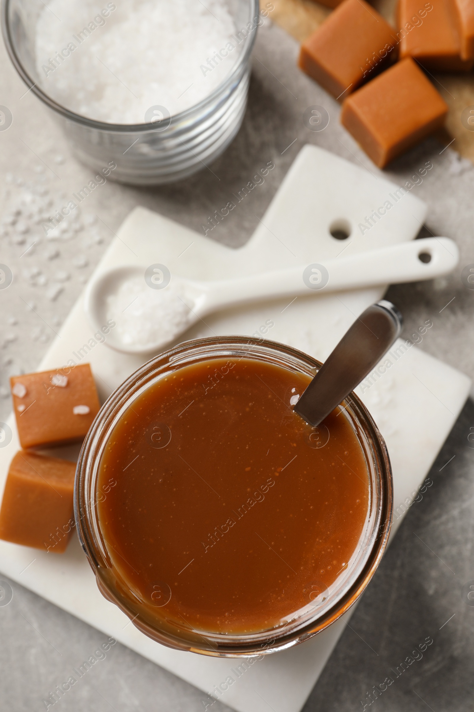 Photo of Tasty salted caramel and candies on light grey table, flat lay