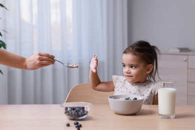 Cute little girl refusing to eat her breakfast at home