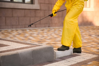 Photo of Person in hazmat suit disinfecting street with sprayer, closeup. Surface treatment during coronavirus pandemic
