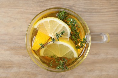 Photo of Glass cup of aromatic herbal tea with thyme and lemon on wooden table, top view