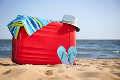 Photo of Bright suitcase and different beach accessories on sand near sea. Space for text