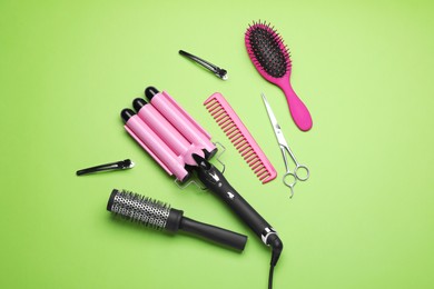 Flat lay composition of different professional hairdresser tools on light green background