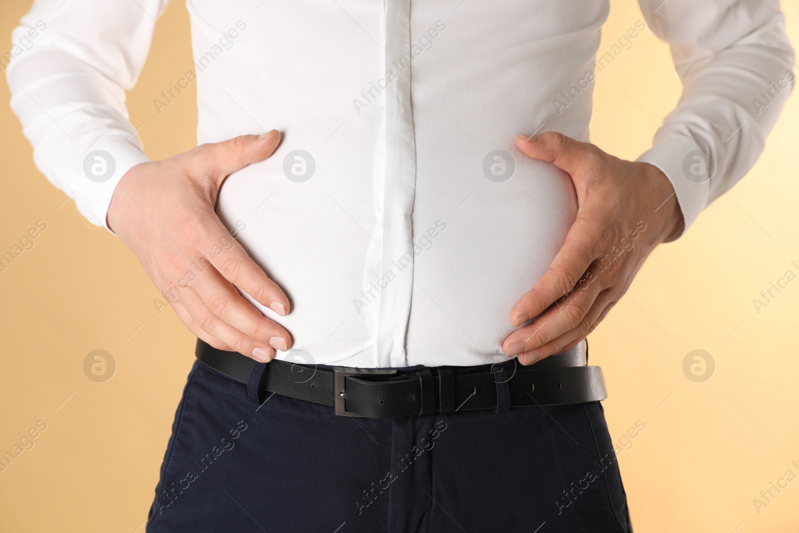 Photo of Overweight man in tight shirt on yellow background, closeup