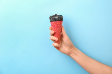 Woman holding yummy ice cream on color background. Focus on hand