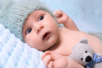 Cute newborn baby with crochet toy on light blue blanket, closeup