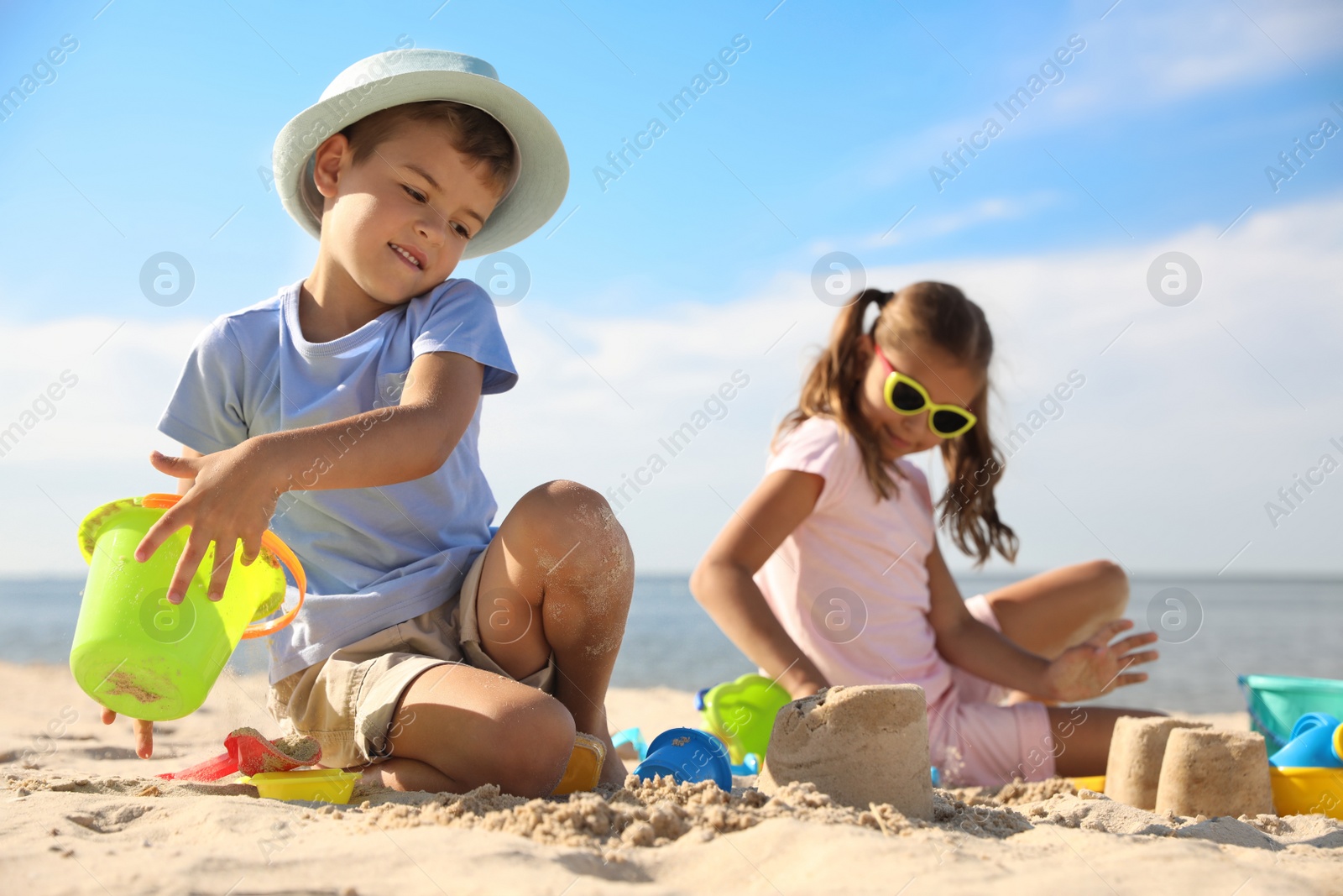 Photo of Cute little children playing with plastic toys on sandy beach