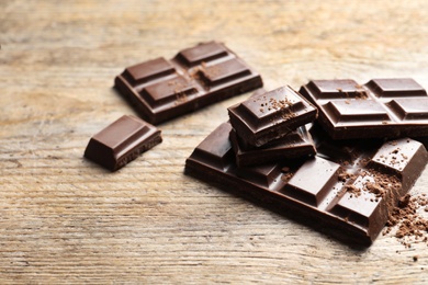 Pieces of chocolate on wooden background. Space for text