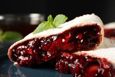 Photo of Delicious strudel with cherries, powdered sugar and mint on plate, closeup