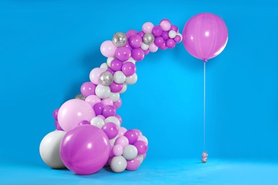 Image of Balloon garland near light blue wall. Festive decor