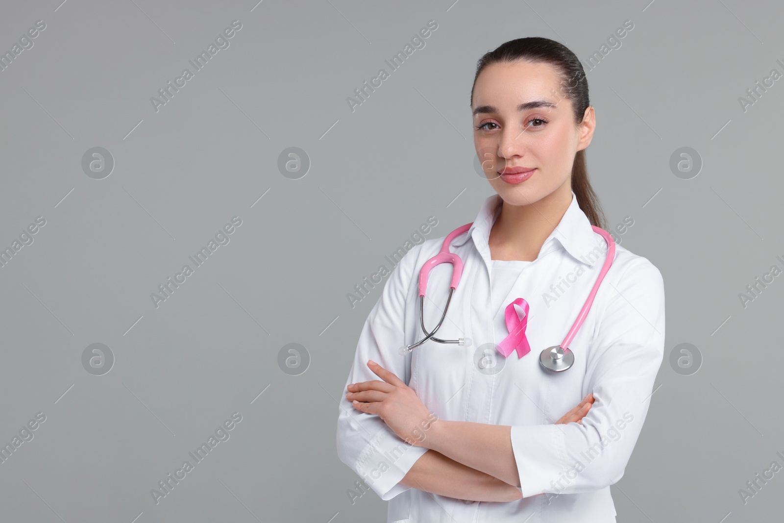 Photo of Mammologist with pink ribbon on gray background, space for text. Breast cancer awareness